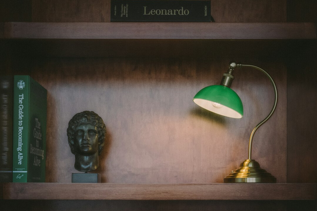 Books arranged on a shelf with a lamp