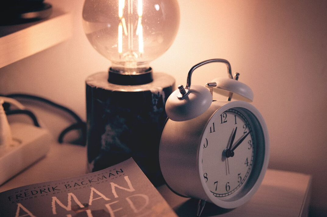Books stacked beside a reading lamp