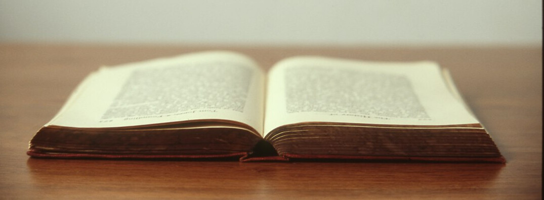 Open book and pen on a wooden desk